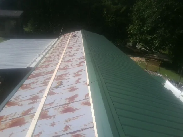 Old rusted panels beside newly installed green metal roofing — Wind Damage Roof Repair by Roofing Brothers in New Providence