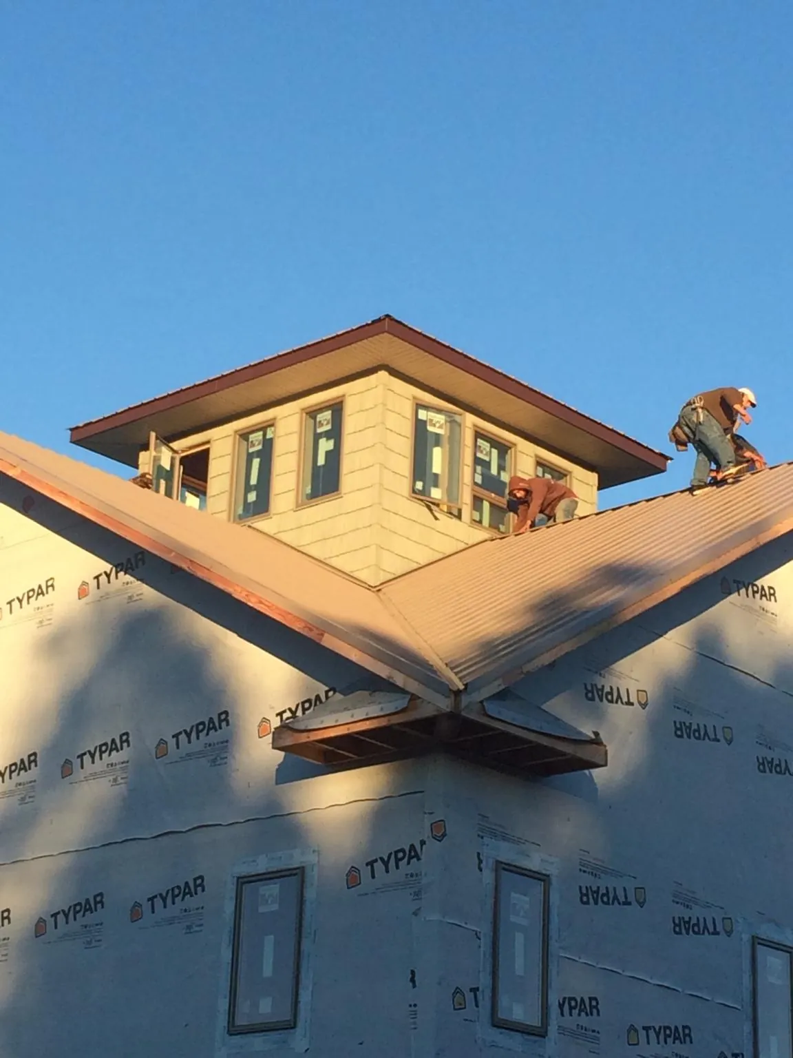 Roofers working around a rooftop cupola on a new metal roof at sunset — Roof Waterproofing in New Providence by Roofing Brothers
